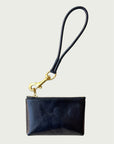 Flat lay of Wildgrain Essential Loop Wrist Strap in Black attached to zipper of Wildgrain Leather Mini Pouch in Black.