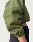 Detail of Contoured Bolero Jacket in Lucid Olive sleeve, side view; voluminous sleeve with double pleats.