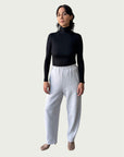Model in Ribbed Mock Neck Shirttail Top in Black with long sleeves and a close, body-skimming fit, styled with the Organic Contoured Cotton Arc Pant in Porcelain.
