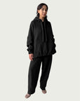 Model in the softly structured Organic Contoured Cotton A.D.C. Hoodie in Black that drapes with ease, styled with Organic Contoured Cotton Arc Pant in Black.