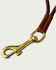 Close up of solid brass trigger hook on Wildgrain Leather Essential Loop Wrist Strap in Cognac.