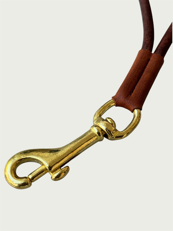 Close up of solid brass trigger hook on Wildgrain Leather Essential Loop Wrist Strap in Cognac.