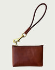 Flat lay of Wildgrain Essential Loop Wrist Strap in Cognac attached to zipper of Wildgrain Leather Mini Pouch in Cognac.