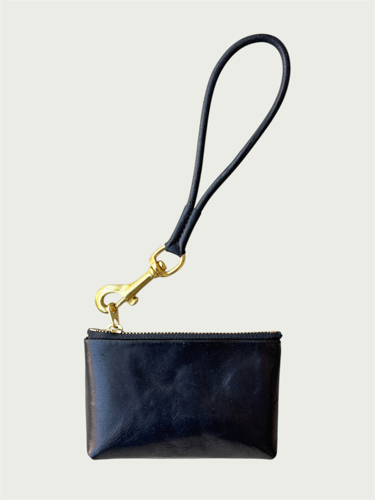Flat lay of Wildgrain Essential Loop Wrist Strap in Black attached to zipper of Wildgrain Leather Mini Pouch in Black.