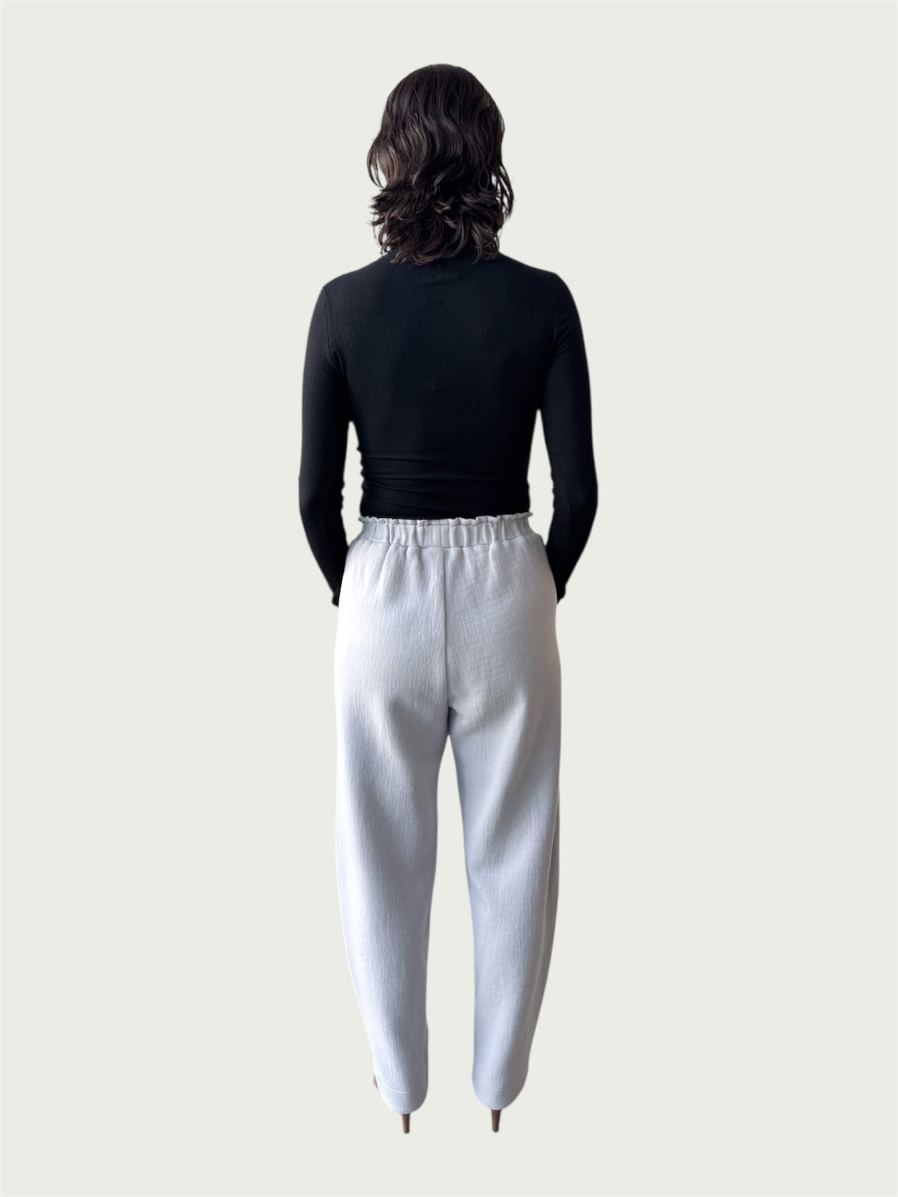 Rear view of Ribbed Mock Neck Shirttail Top in Black on model, seamlessly tucked into the Organic Contoured Cotton Arc Pant in Porcelain.