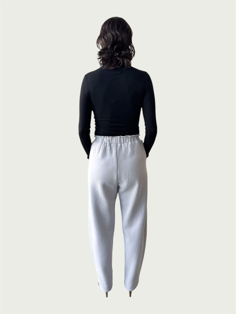 Rear view of Ribbed Mock Neck Shirttail Top in Black on model, seamlessly tucked into the Organic Contoured Cotton Arc Pant in Porcelain.