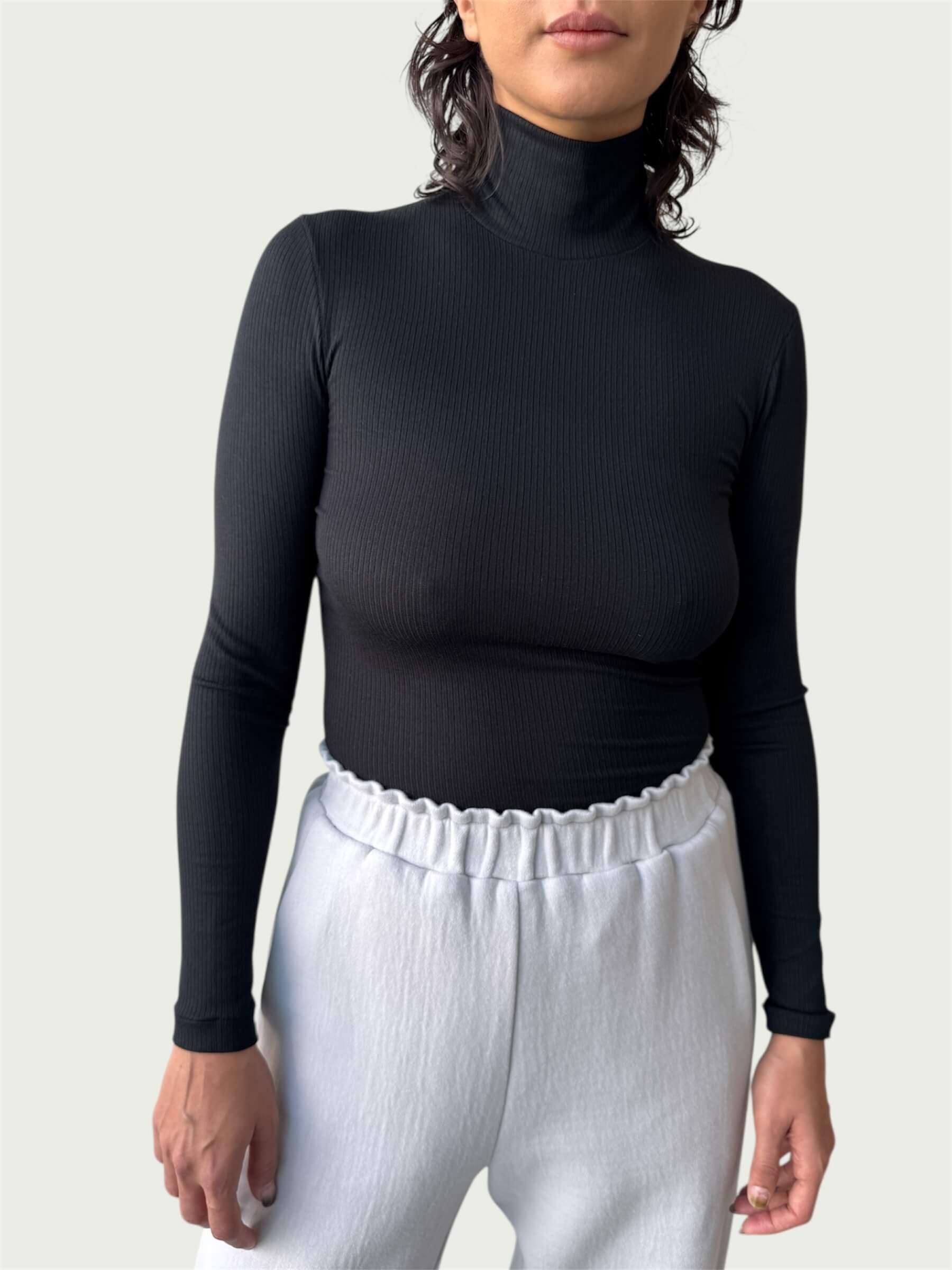 Close-up of lightweight, ribbed stretch fabric, featuring the mock-to-turtleneck neckline on the Ribbed Mock Neck Shirttail Top in Black.