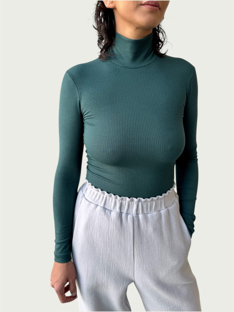 Close-up of lightweight, ribbed stretch fabric, featuring the mock-to-turtleneck neckline on the Ribbed Mock Neck Shirttail Top in Silver Pine.