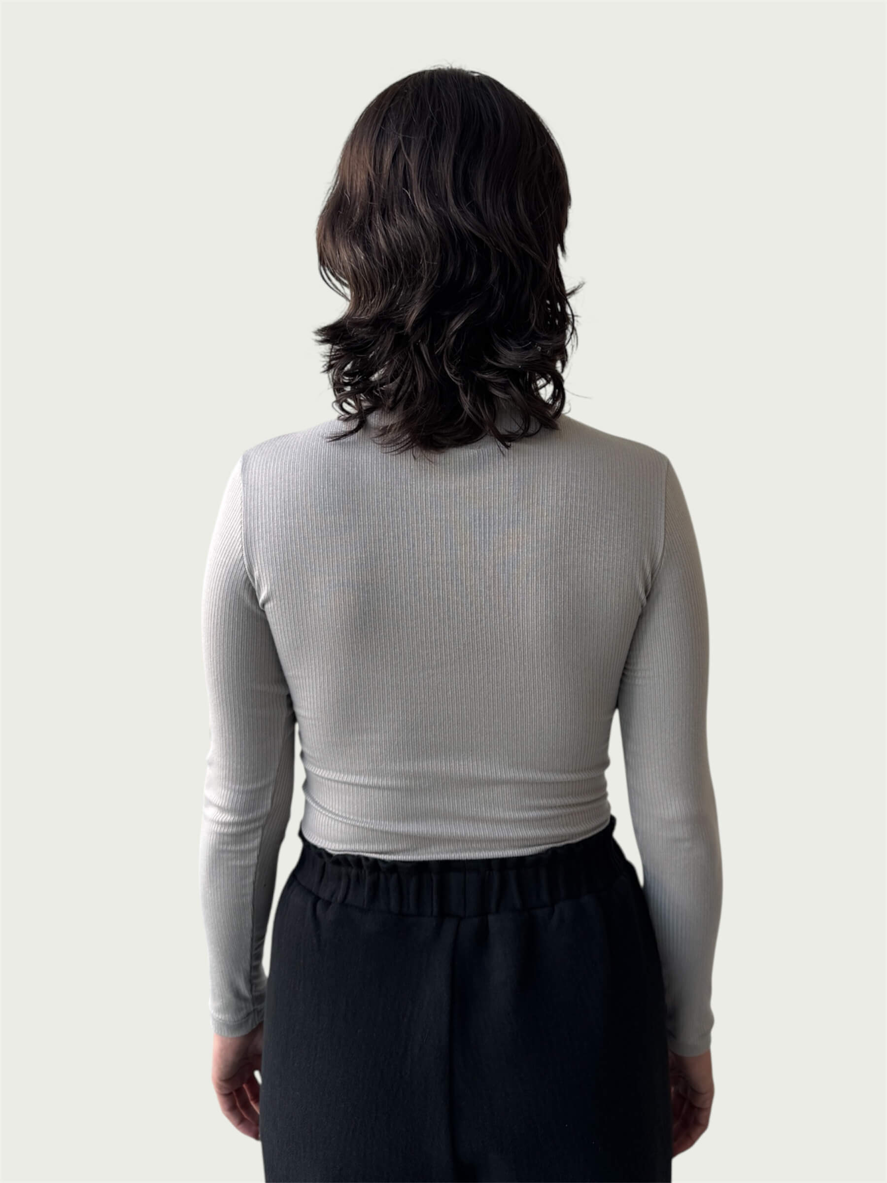 Rear view of Ribbed Mock Neck Shirttail Top in Dove Grey on model, seamlessly tucked into the Organic Contoured Cotton Arc Pant in Black.