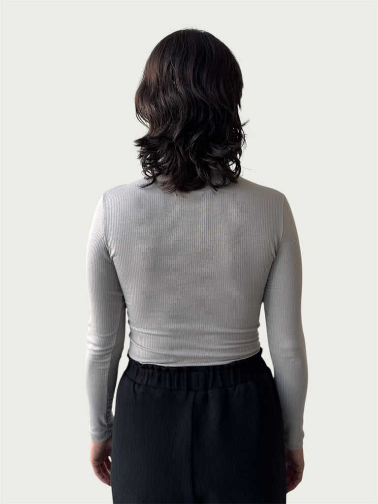 Rear view of Ribbed Mock Neck Shirttail Top in Dove Grey on model, seamlessly tucked into the Organic Contoured Cotton Arc Pant in Black.