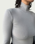 Close-up of lightweight, ribbed stretch fabric, featuring the mock-to-turtleneck neckline on the Ribbed Mock Neck Shirttail Top in Dove Grey.