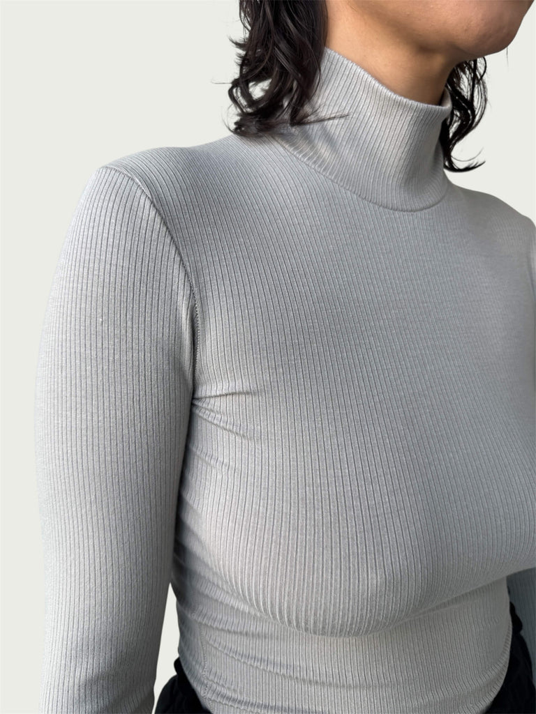 Close-up of lightweight, ribbed stretch fabric, featuring the mock-to-turtleneck neckline on the Ribbed Mock Neck Shirttail Top in Dove Grey.