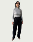 Model in Ribbed Mock Neck Shirttail Top in Dove Grey with long sleeves and a close, body-skimming fit, styled with the Organic Contoured Cotton Arc Pant in Black.