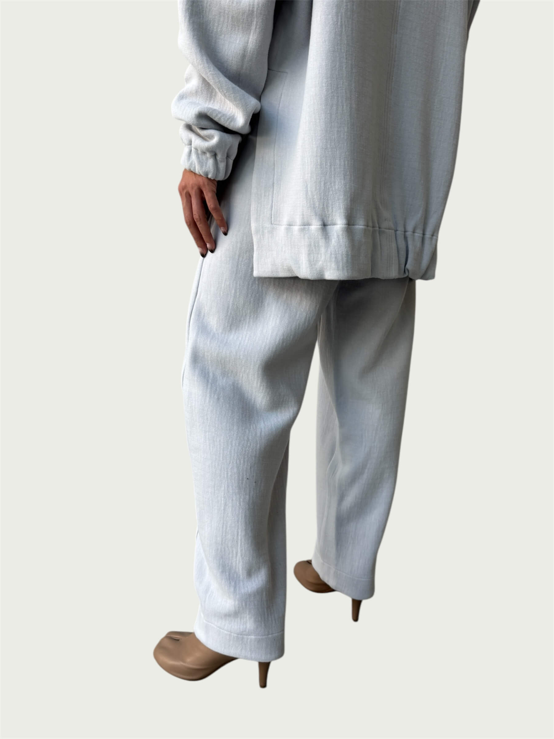 Rear view of gently gathered hem with side slits on Organic Contoured Cotton A.D.C. Hoodie in Porcelain, styled with Organic Contoured Cotton Arc Pant in Porcelain.