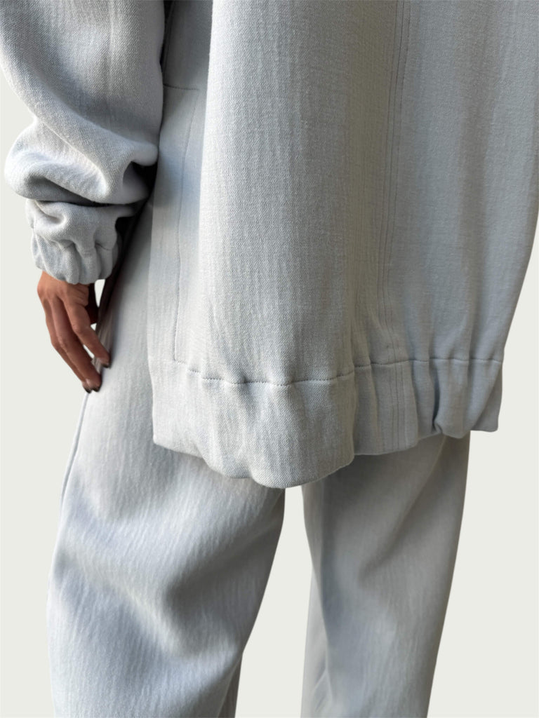 Rear view of gently gathered hem with side slits on Organic Contoured Cotton A.D.C. Hoodie in Porcelain, styled with Organic Contoured Cotton Arc Pant in Porcelain.