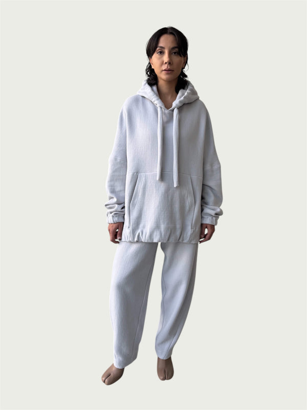 Model in the softly structured Organic Contoured Cotton A.D.C. Hoodie in Porcelain that drapes with ease, styled with Organic Contoured Cotton Arc Pant in Porcelain.