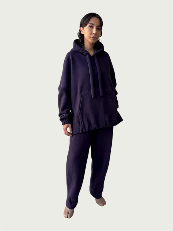 Model in Organic Contoured Cotton A.D.C. Hoodie in Evening Violet with in-seam Kangaroo pocket and double layered hood, styled with Organic Contoured Cotton Arc Pant in Evening Violet.