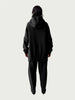 Rear view of model in Organic Contoured Cotton A.D.C. Hoodie in Black with gently gathered hem, falling below the hip; styled with Organic Contoured Cotton Arc Pant in Black.