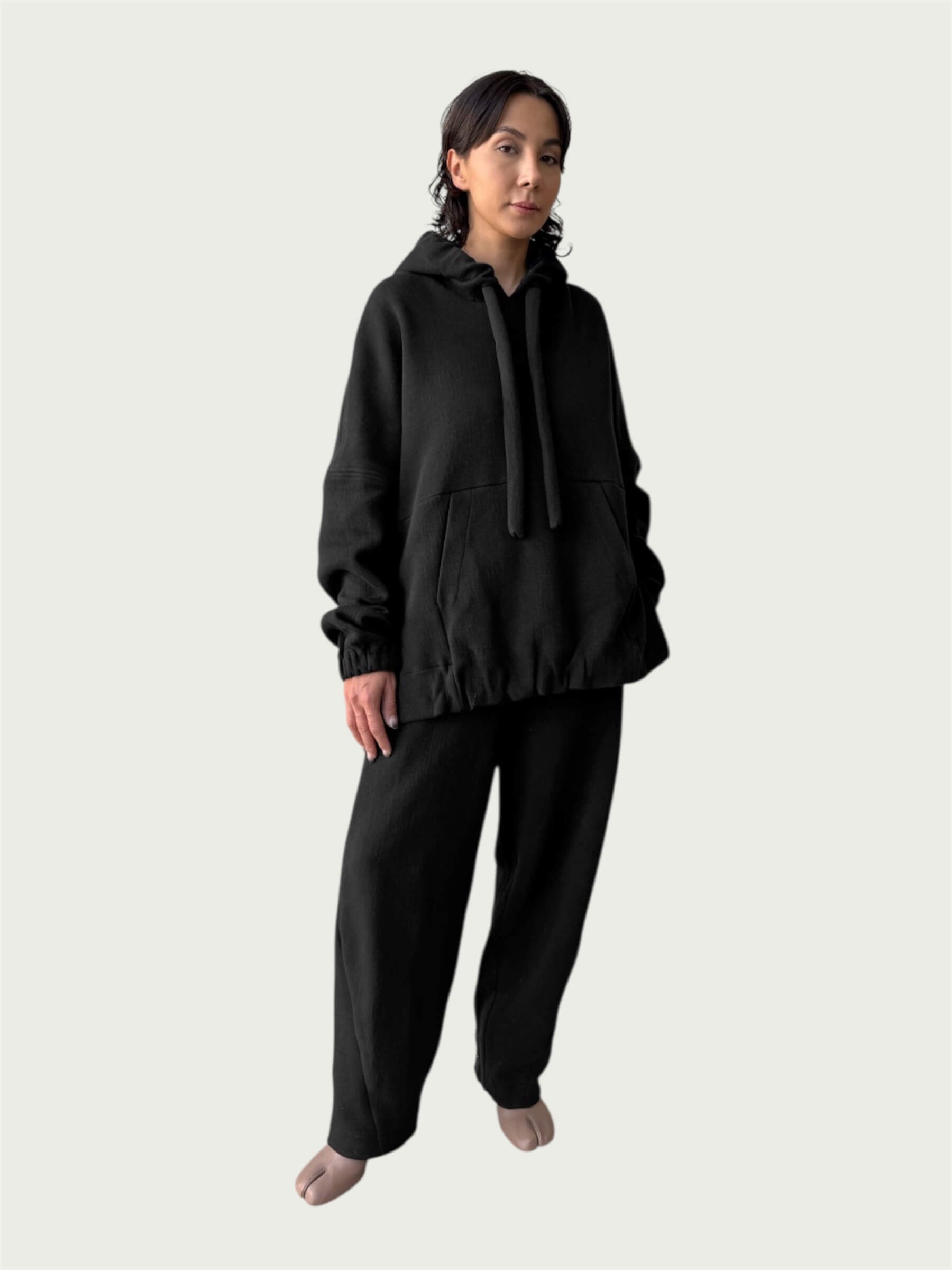 Model in the softly structured Organic Contoured Cotton A.D.C. Hoodie in Black that drapes with ease, styled with Organic Contoured Cotton Arc Pant in Black.