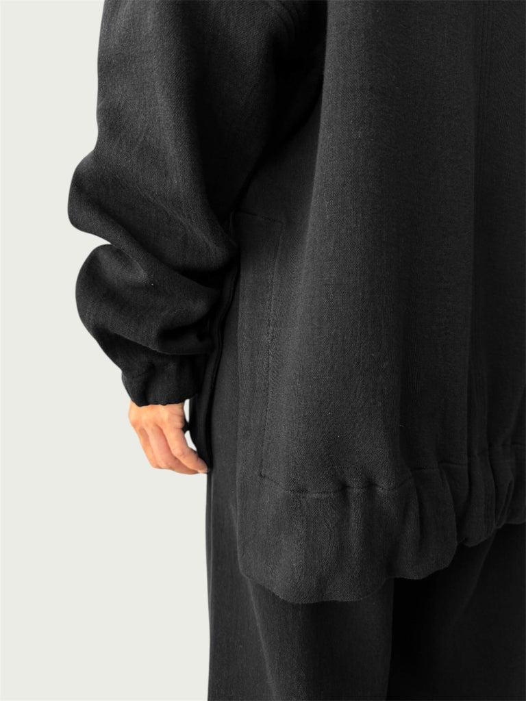Detail of high-low hemline with side slit on Organic Contoured Cotton A.D.C. Hoodie in Black, showcasing its easy drape.