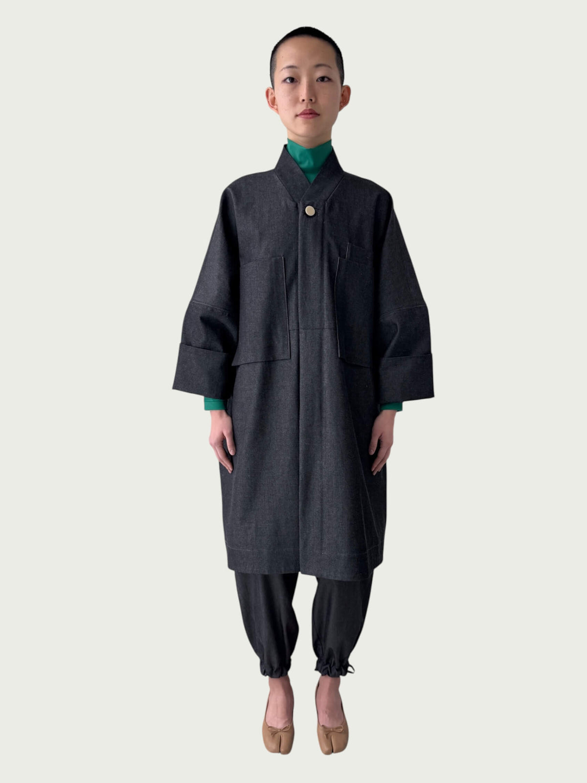 Person wearing a dark coat and pants on a white background