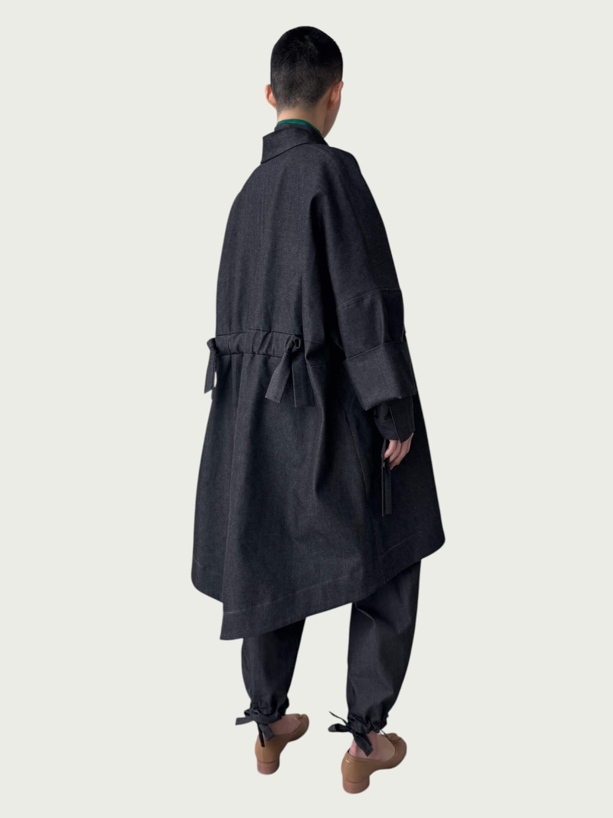 Person wearing a dark gray coat and pants on a white background