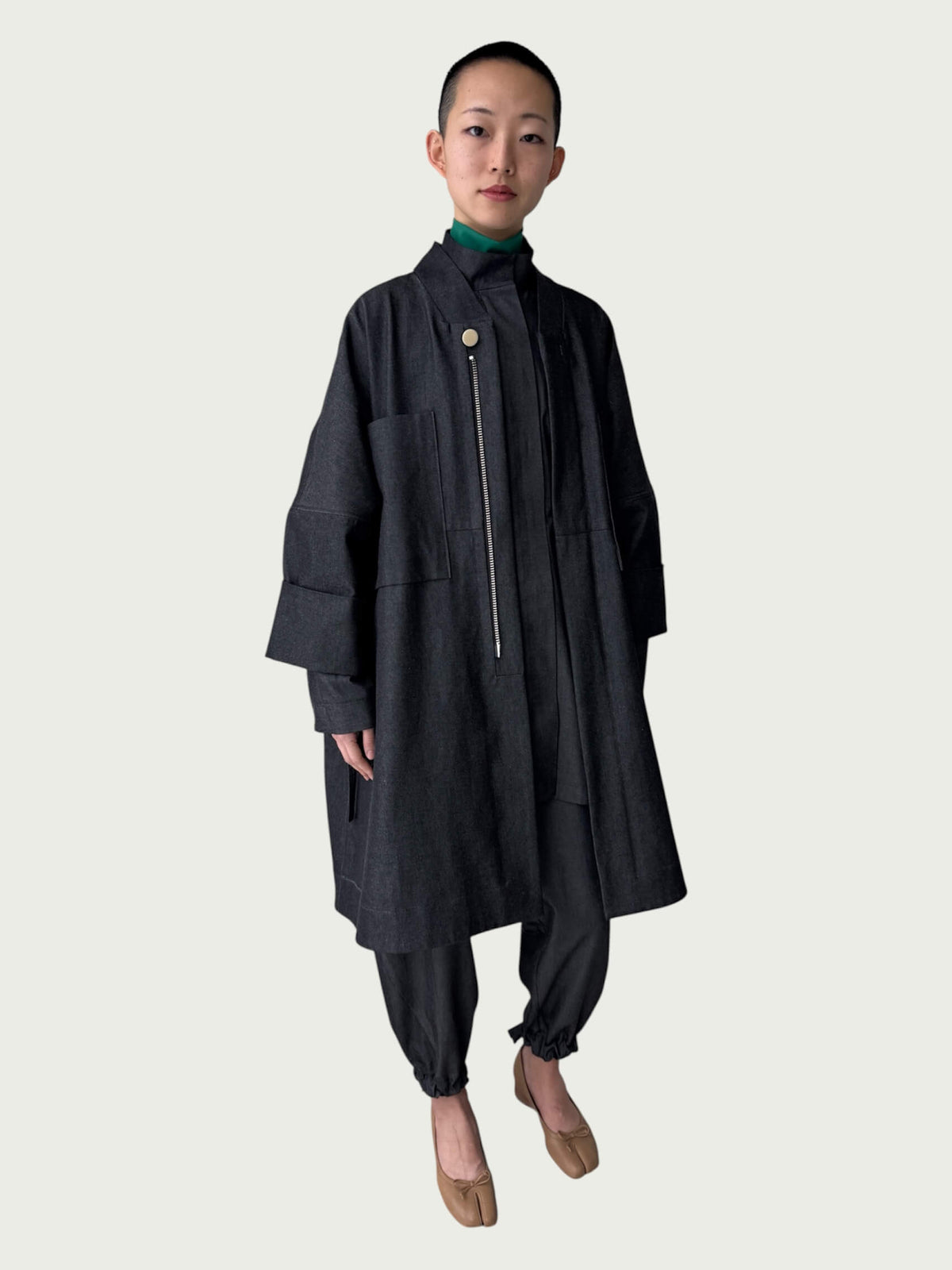 Person wearing a dark coat and pants on a white background