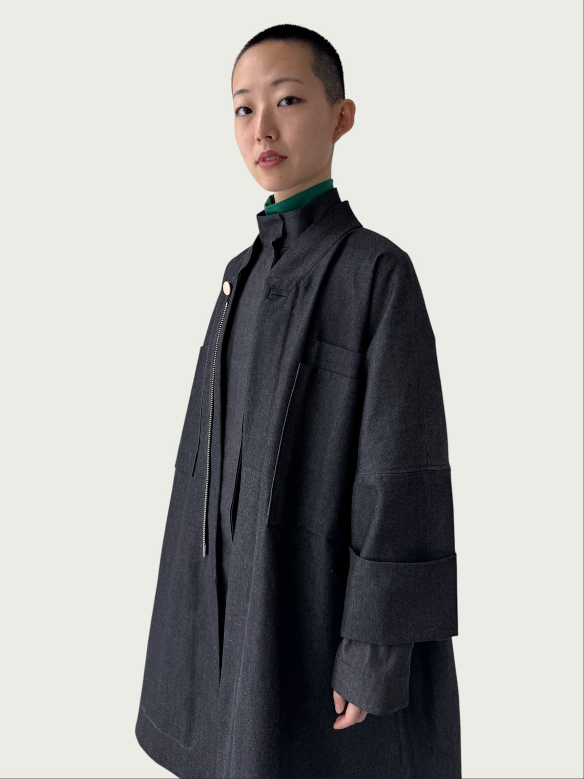 Person wearing a black denim coat on a plain background
